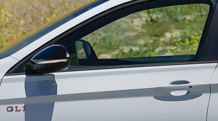 Gros plan sur la portière du côté conducteur de la Jetta GLI de Volkswagen, mettant en valeur la fonction d'accès sans clé KESSY avec un bouton de démarrage.