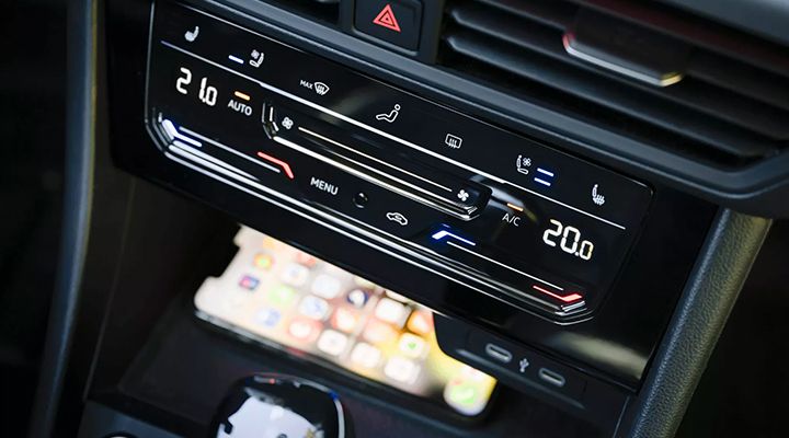 Close-up of the VW Jetta's center console, highlighting the wireless device charging area beneath the climate controls.