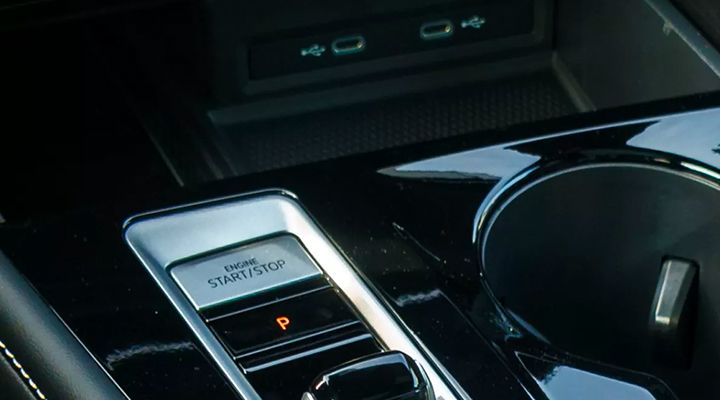 Close-up of the vehicle's "Engine Start/Stop" button and cup holders, with USB-C charging ports visible above.