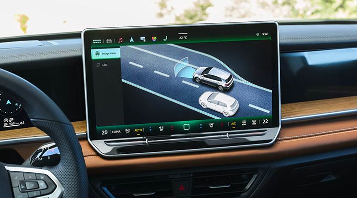Infotainment screen showing the driving assistance display (Travel Assist), illustrating two cars on the road with detection zones.