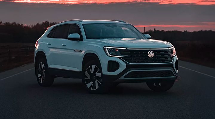Front view of a white Volkswagen Atlas or Atlas Cross Sport parked on a dark road at sunset or dawn.