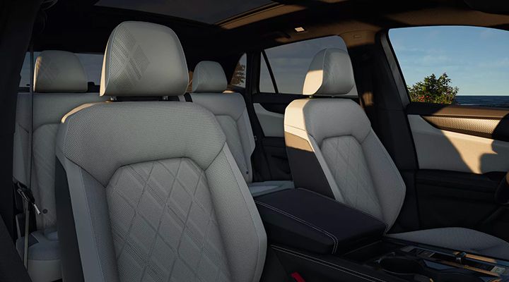 Interior view showing the front and second-row seats of a vehicle, upholstered in light grey leather or leatherette with a diamond quilted pattern.