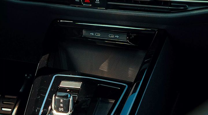 Close-up of a car's center console, showing a storage compartment with USB-C ports for charging.