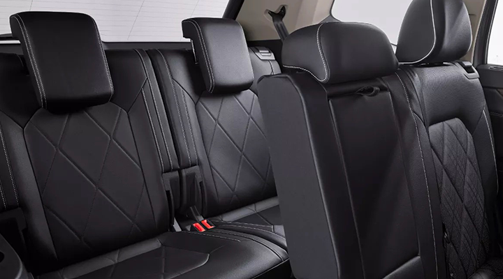 Close-up of the third-row seats of an SUV, featuring black leatherette with a quilted pattern and white stitching.