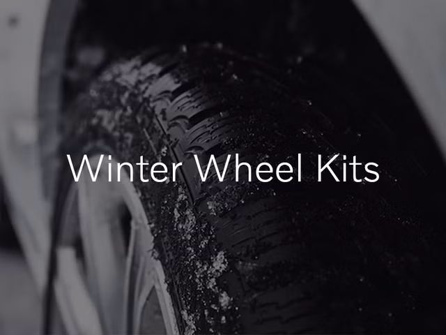 A close-up shot of a black winter tire with snow dusting its treads. The text "Winter Wheel Kits" is overlaid on the image.