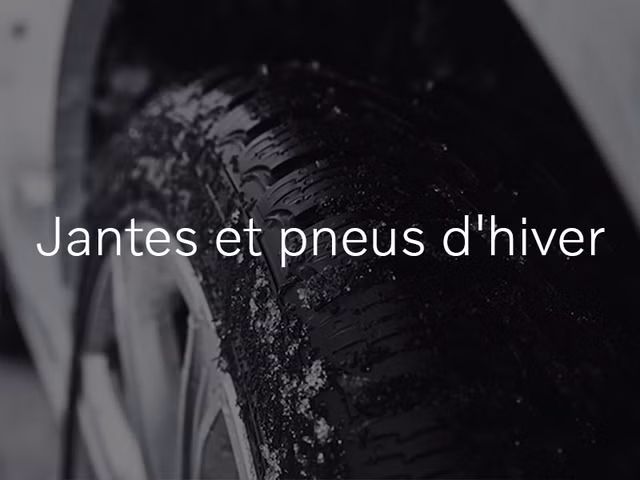 Un gros plan d'un pneu d'hiver noir avec de la neige sur la bande de roulement. Le texte « Jantes et pneus d'hiver » est superposé sur l'image.