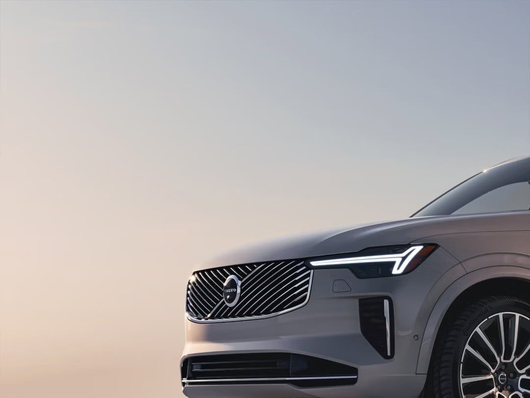 A close-up on the front grille and modern LED headlight of a silver Volvo EX90.