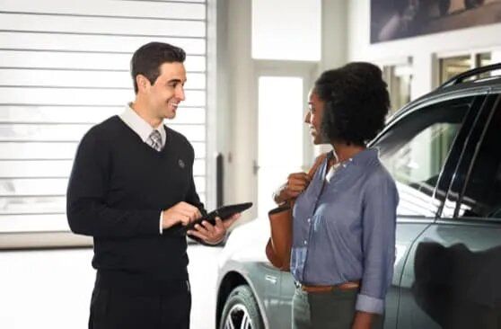 Mercedes-Benz advisor with tablet speaking with a female customer at a dealership