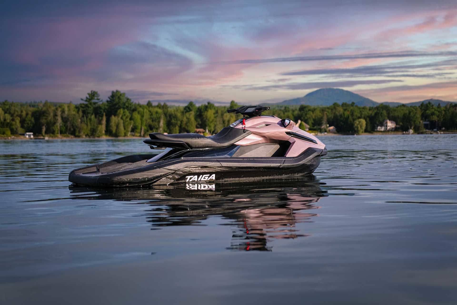 Man riding an orange and black jet ski on a river with the Montreal skyline in the background.	
