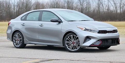A gray Kia Forte sedan parked on an open field.