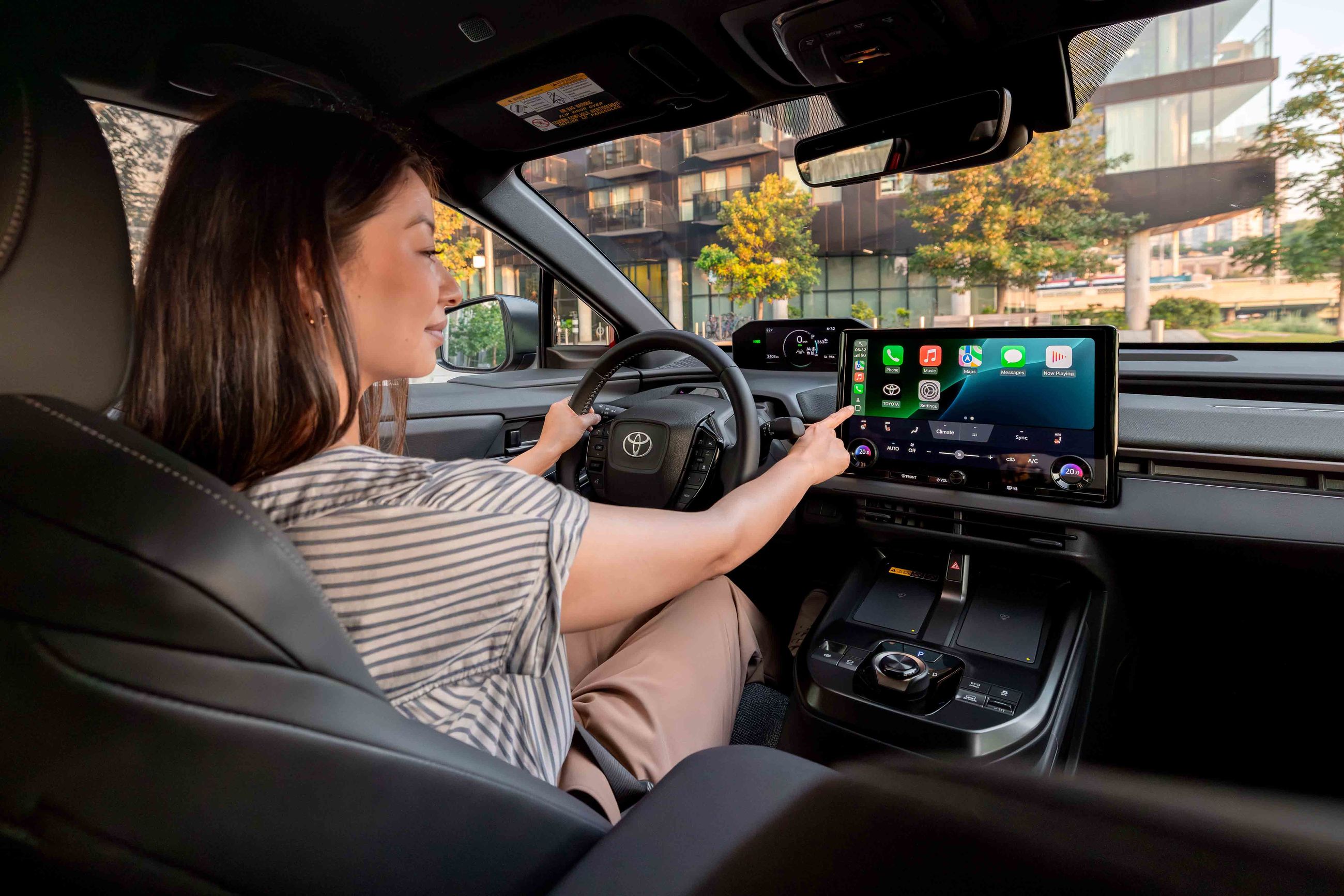 Smiling car salesman in a suit, holding a tablet in a dealership showroom.