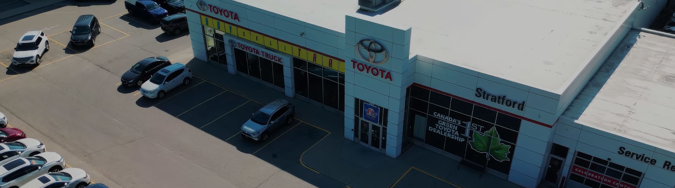 Row of new cars in a dealership showroom, with a red car in the foreground.