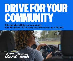 Mechanic giving a thumbs-up sign over a car engine.