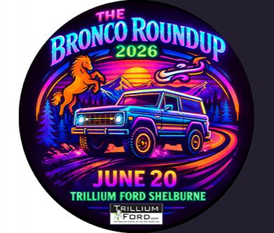 Smiling man wearing a red blazer, standing in a car dealership showroom.