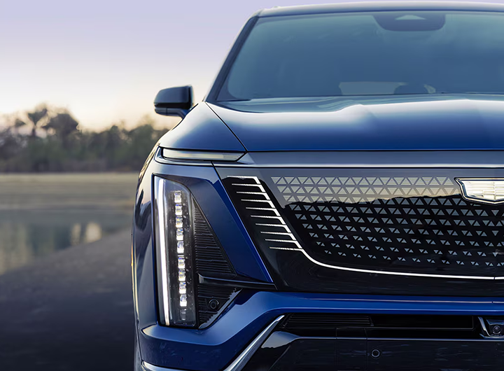 Close-up of the front grille and vertical LED headlight of a blue Cadillac.
