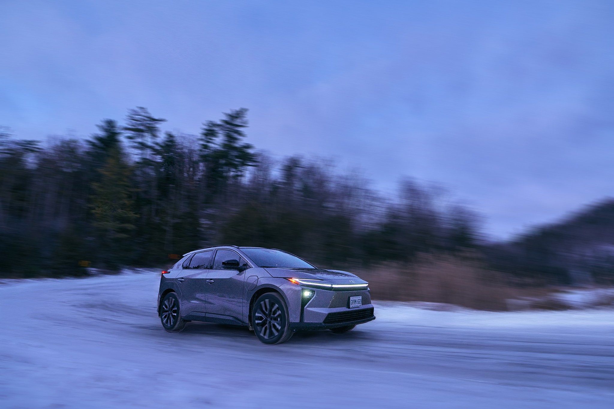 Smiling car salesman in a suit, holding a tablet in a dealership showroom.
