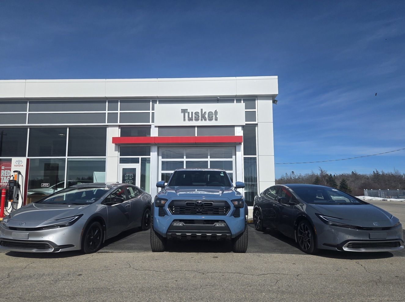 Smiling man wearing a red blazer, standing in a car dealership showroom.