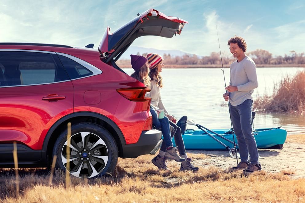 riends relaxing by a lake with a kayak and a red Ford Escape SUV with its trunk open.