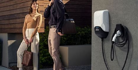 A couple walking past a wall-mounted Ford Connected Charge Station installed on the exterior of a modern home.