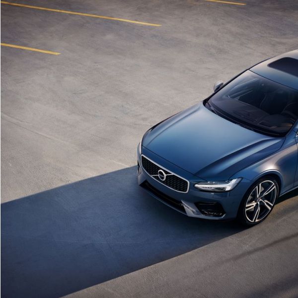 An angled, high-overhead shot of a blue Volvo sedan parked in a concrete parking lot, with yellow lines visible.
