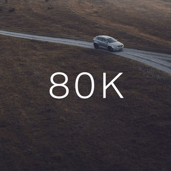 A silver SUV drives on a winding dirt road through a hilly, brown landscape, with the large white text "80K" overlaid.