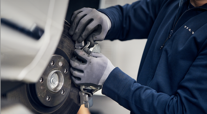 Mechanic giving a thumbs-up sign over a car engine.
