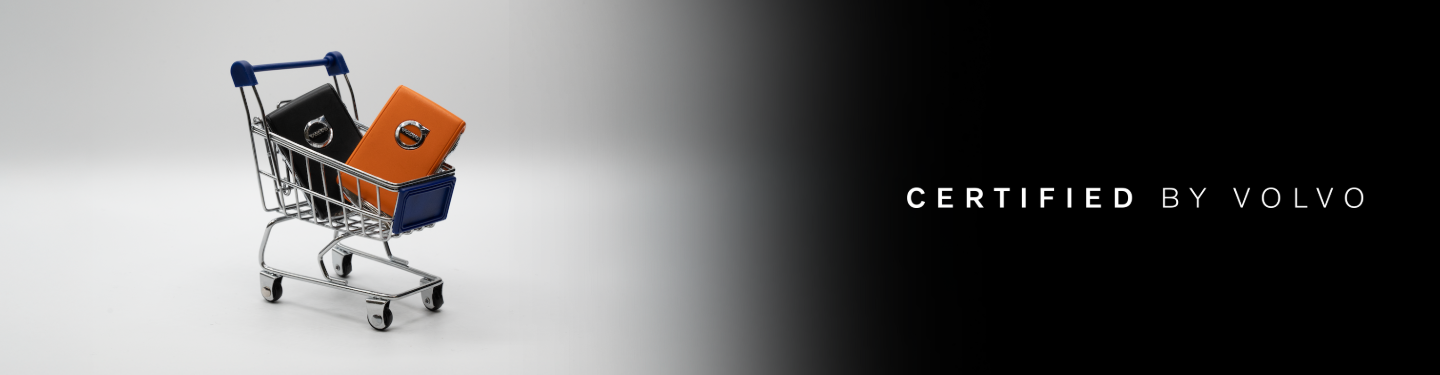 A smiling female salesperson and a male customer look at a clipboard together inside a bright car dealership showroom.