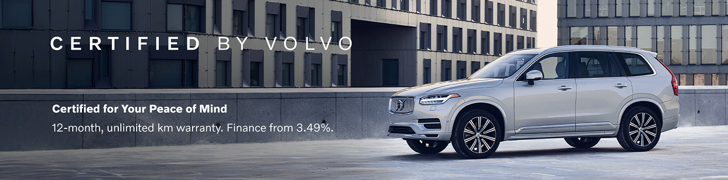 A smiling female salesperson and a male customer look at a clipboard together inside a bright car dealership showroom.