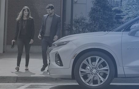 Man and woman walking together beside a parked white SUV.